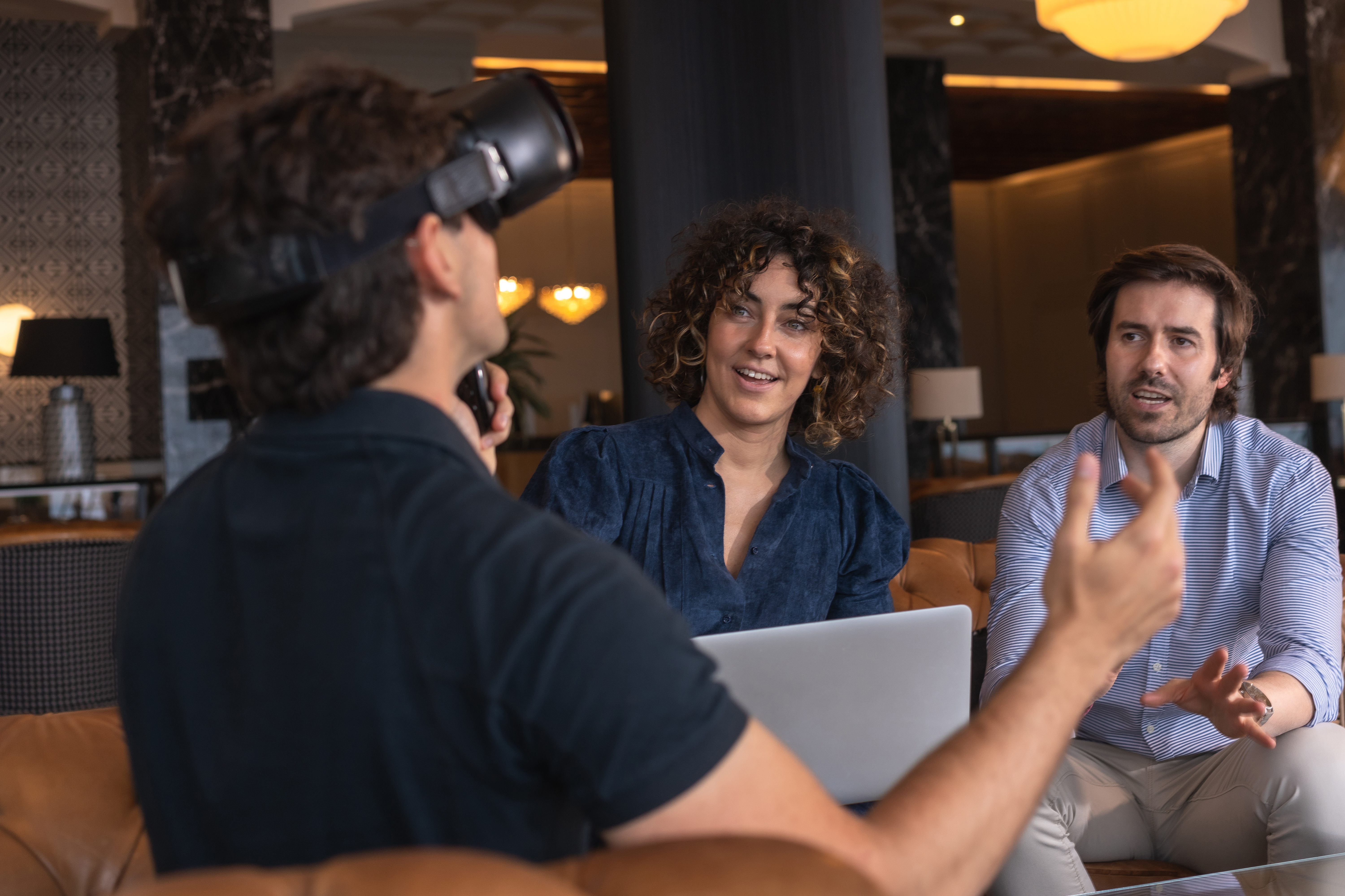 businesswoman-using-laptop-with-colleague-gesturing-by-wearing-virtual-reality-simulator